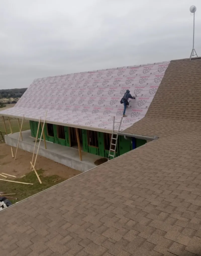 Worker preparing underlayment for a metal roof installation in Moraga